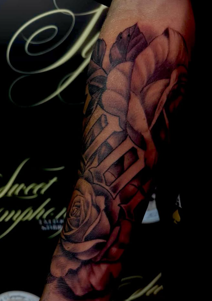 Black-and-grey realism forearm sleeve with a large rose and bold lettering.