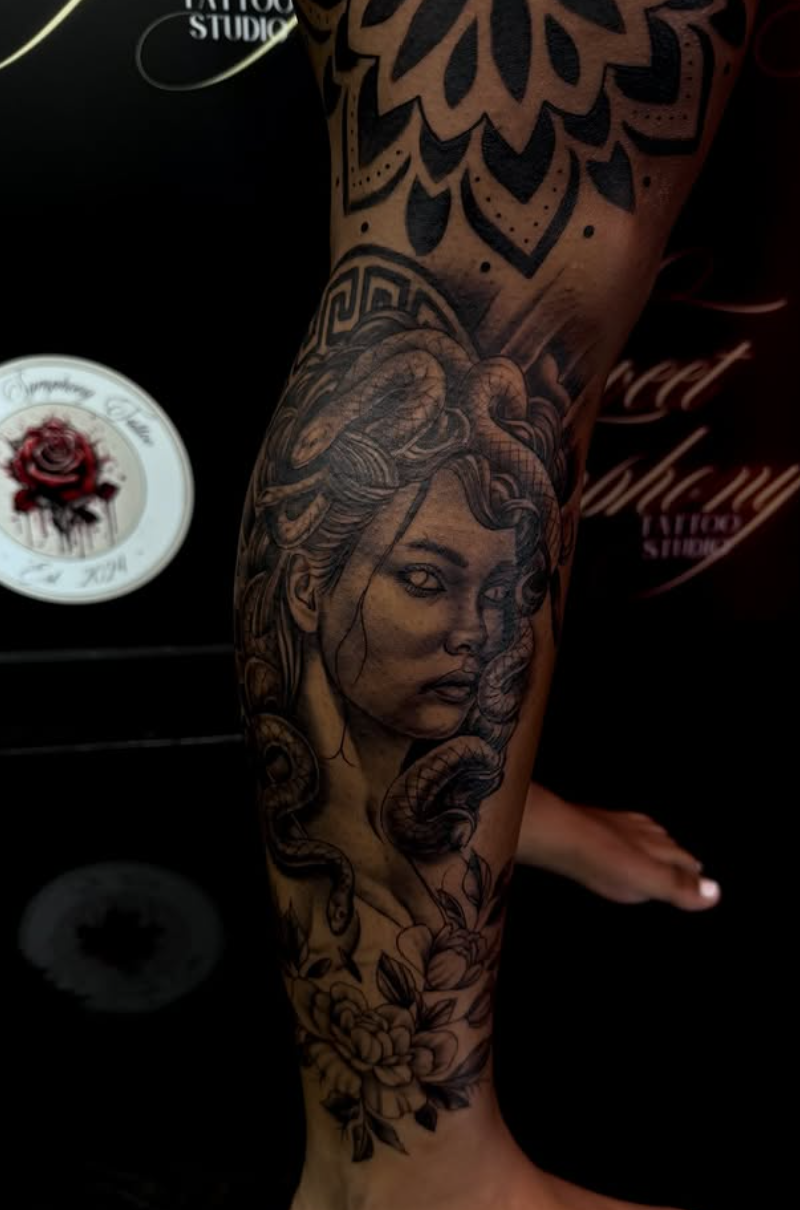 Black-and-grey realistic Medusa portrait tattoo with detailed snake hair on the calf.