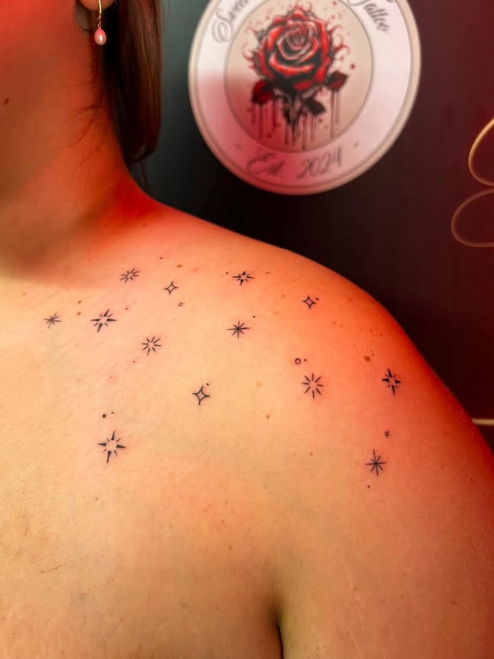 Minimalist scattered star cluster tattoo across the shoulder.