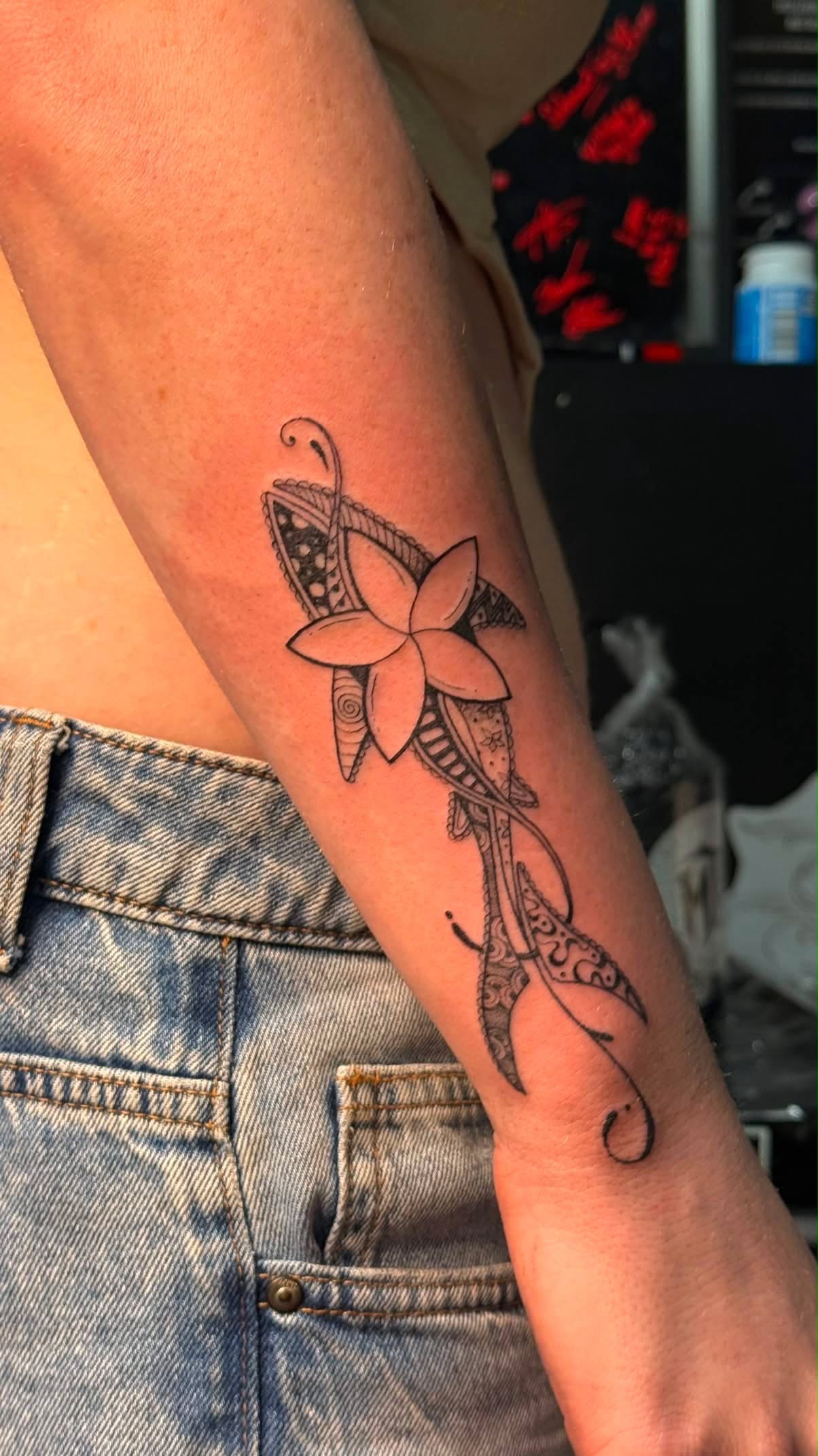 Ornamental blackwork flower tattoo with patterned detail on the forearm.
