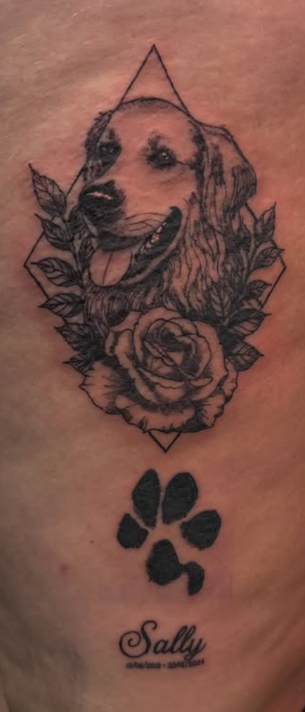 Dotwork realism portrait of a dog with a rose and paw print memorial tattoo.