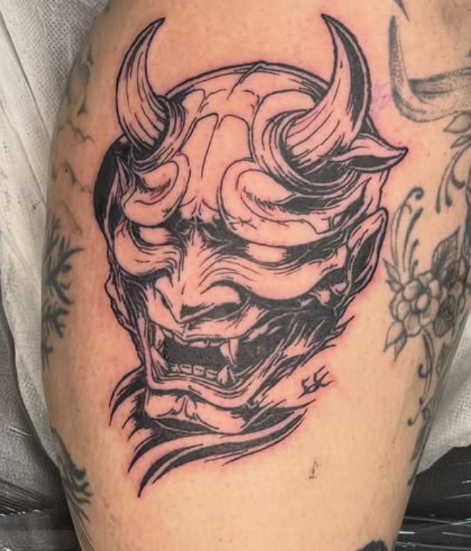 Bold blackwork Japanese hannya mask tattoo on the calf.